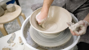shaping a clay bowl on a spinning potter's wheel