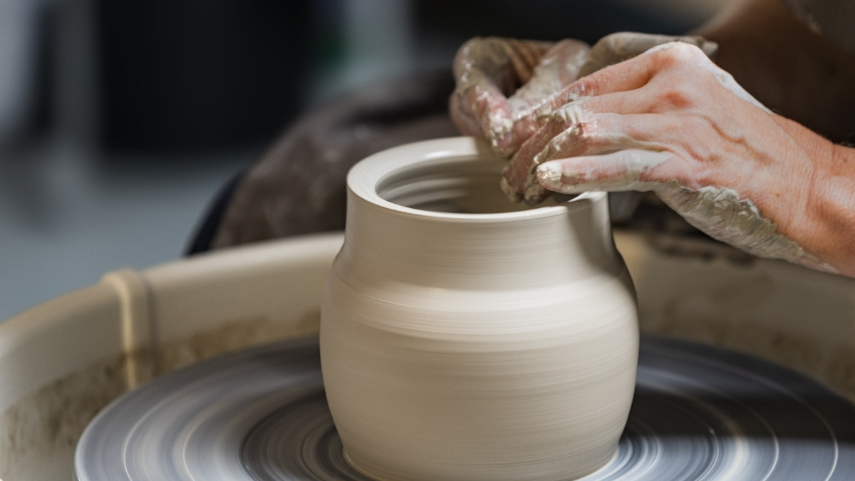 unglazed ceramic pot being shaped on a pottery wheel