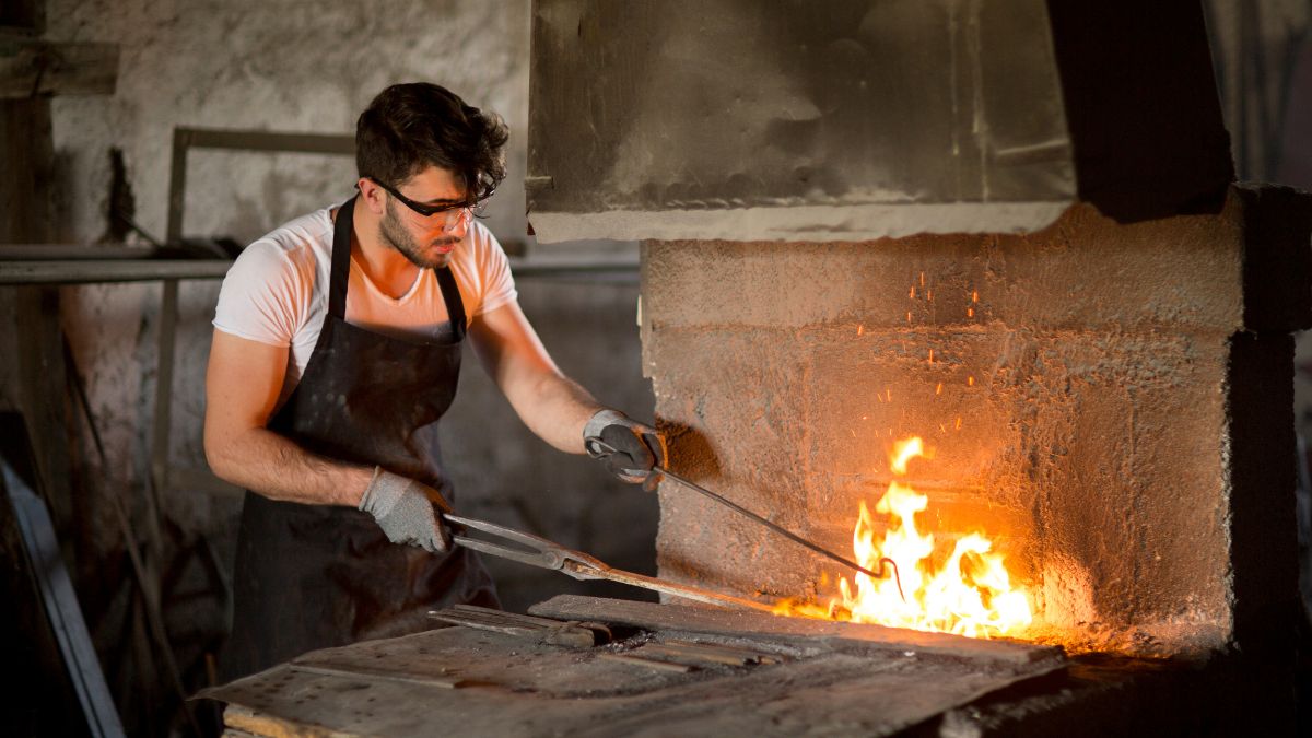 Blacksmith heating metal in a flaming forge workshop