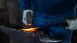 blacksmith striking a glowing, hot metal rod