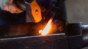 Hammer striking glowing metal rod.