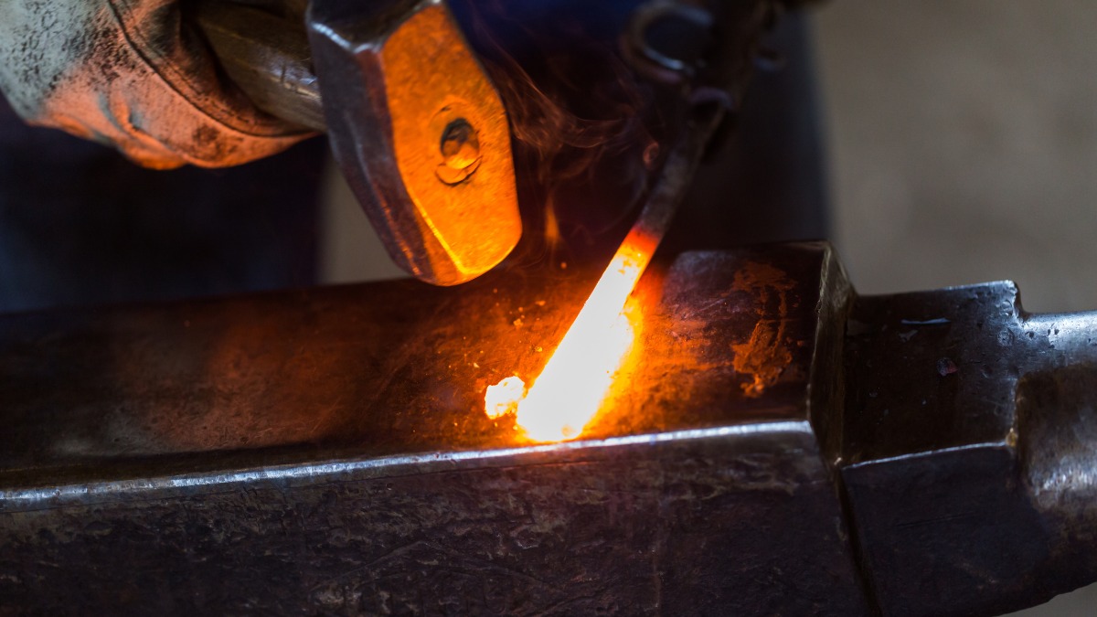 Hammer striking glowing metal rod.