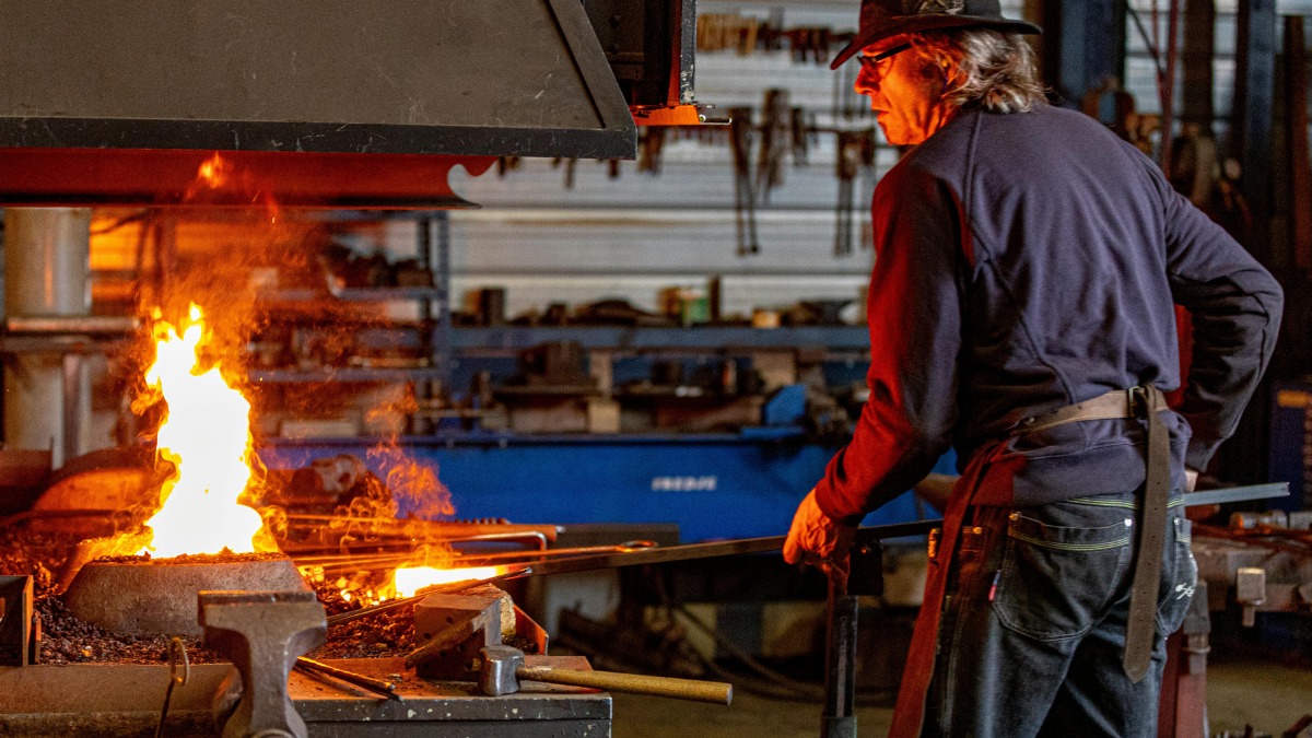 Blacksmith heating metal in forge.