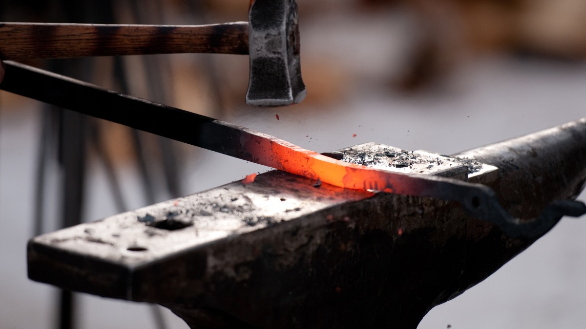 hot iron bar with a hammer on an anvil