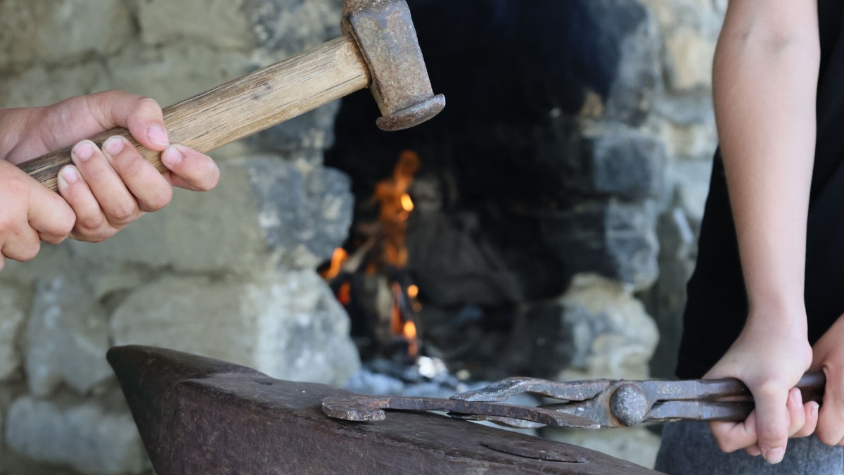 Close-up of hands holding a vintage blacksmithing hammer