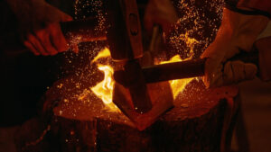 Hammer striking glowing hot metal on anvil