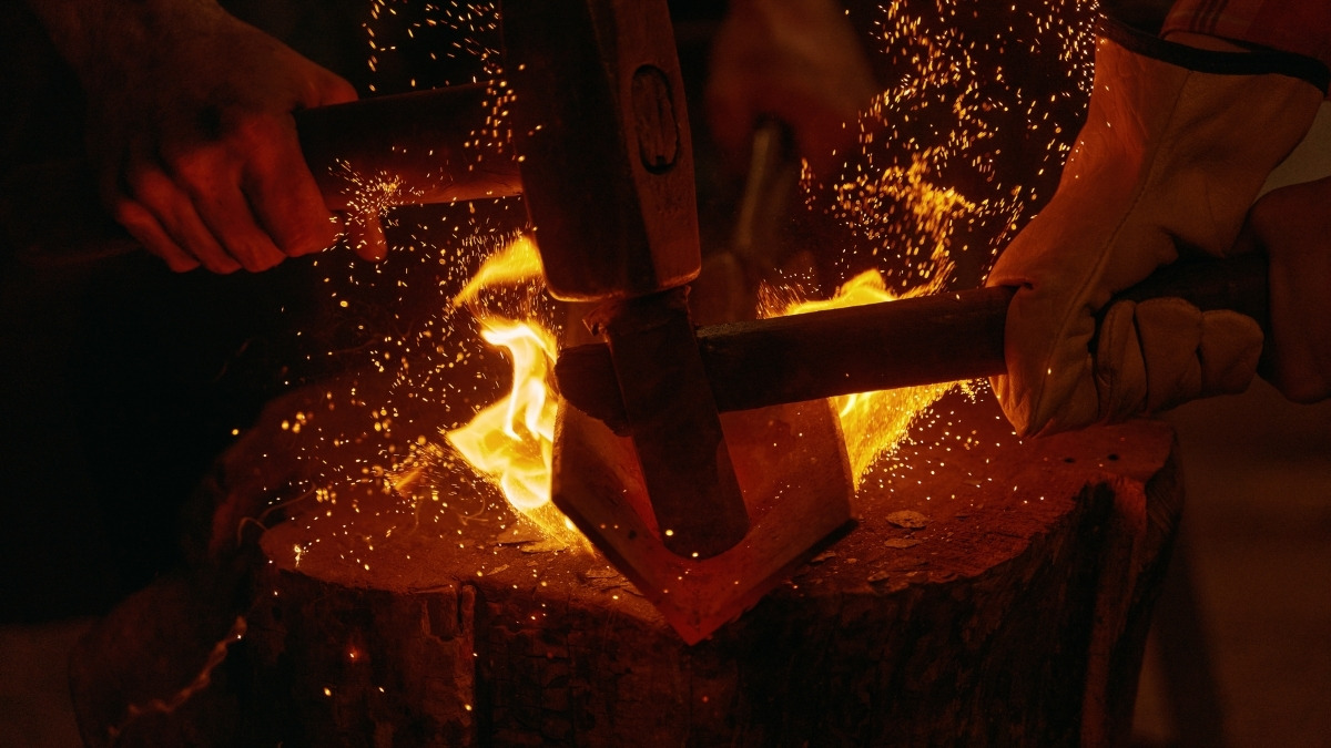 Hammer striking glowing hot metal on anvil