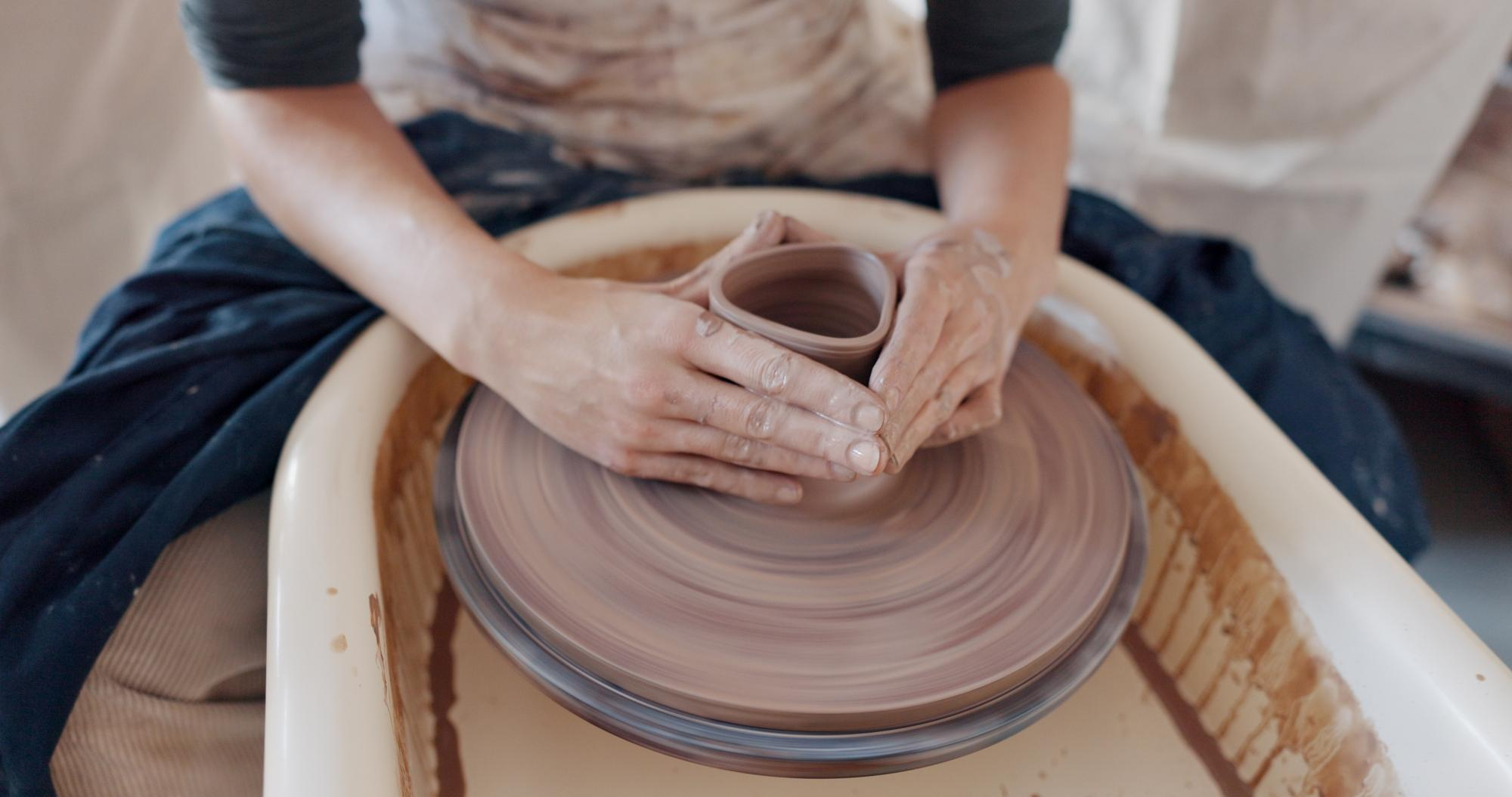 gently shaping a spinning clay vessel