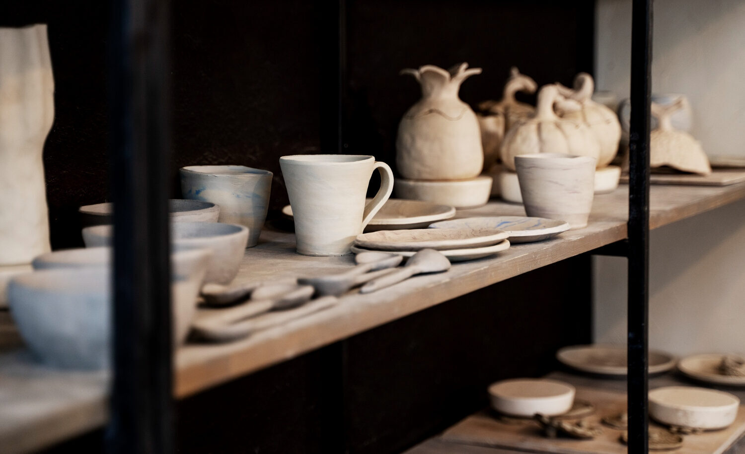 An assortment of unfinished, light gray ceramic mugs