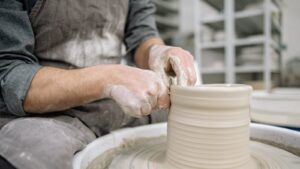 Potter shaping clay on a pottery wheel, showcasing artisan skill indoors