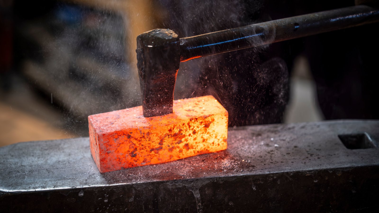 Blacksmith using a hammer to forge a glowing hot metal piece on an anvil, demonstrating skilled metalworking.