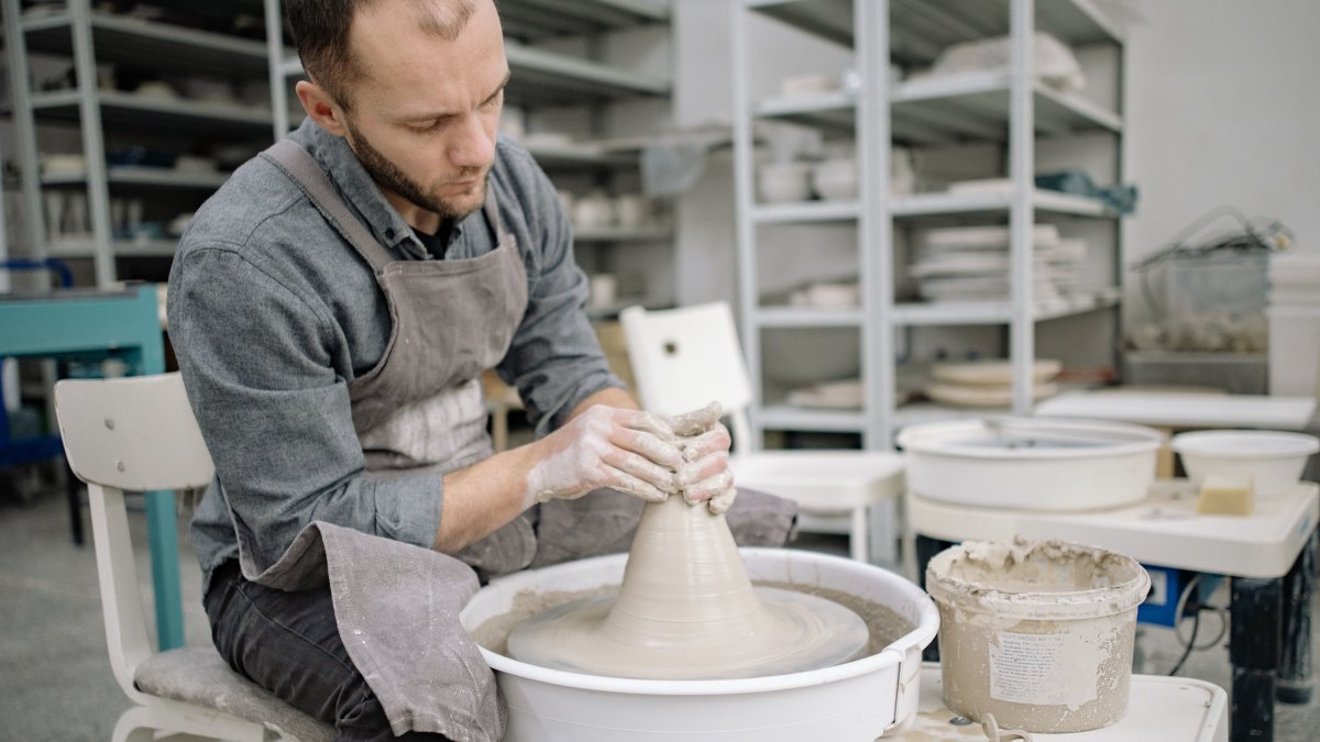 A focused potter crafting pottery on a wheel in an artisan workshop setting