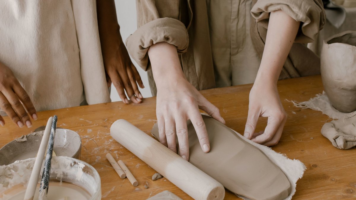 Hands shaping clay at a pottery workshop, emphasizing artisanal craftsmanship.