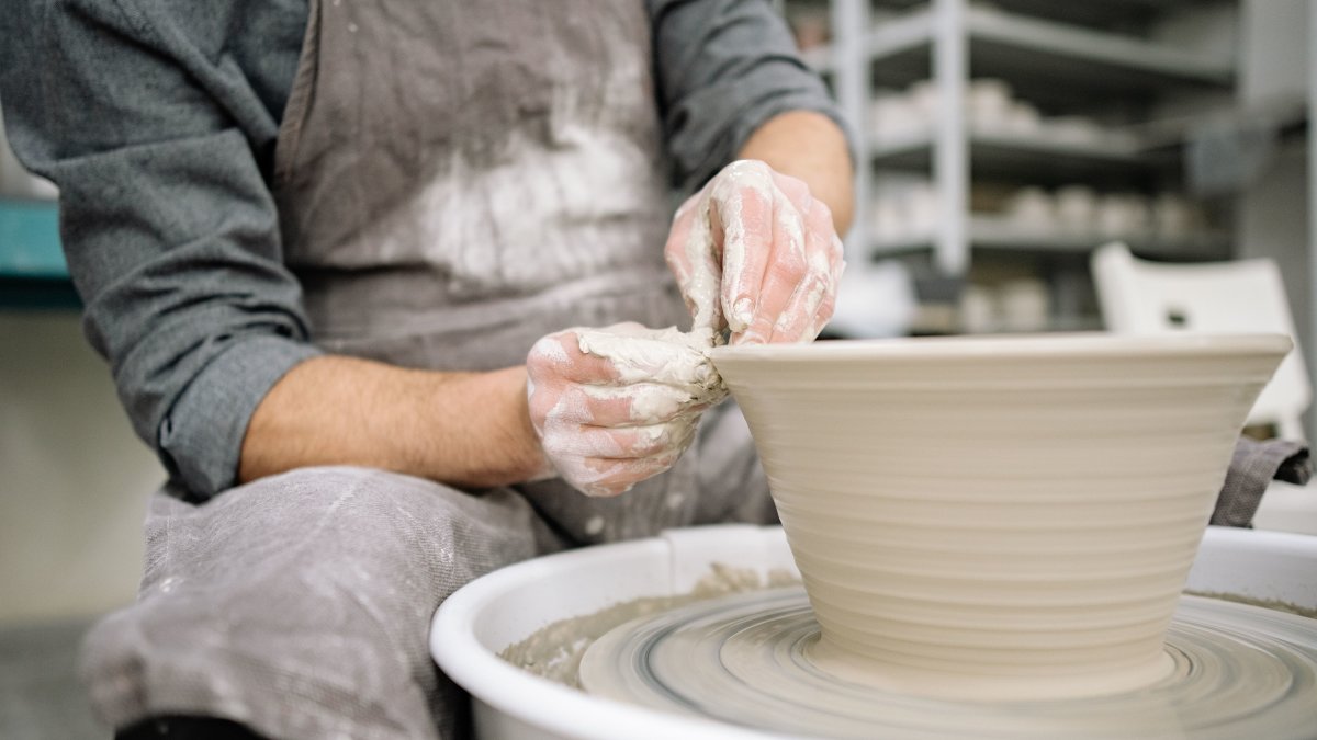 Artisan shaping clay on a potter's wheel in a workshop, showcasing skill and craftsmanship
